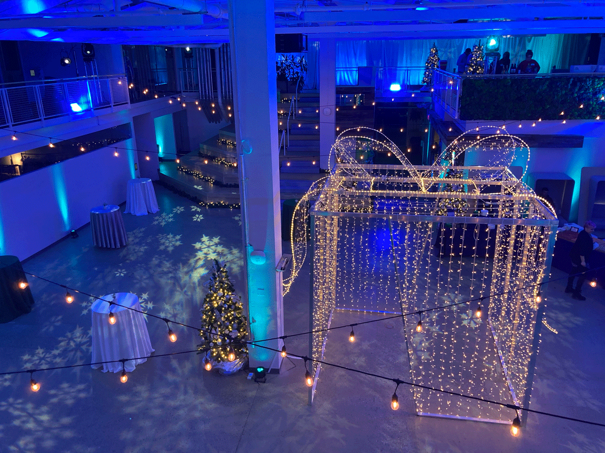 A room is washed in blue light and a giant present is wrapped in lights