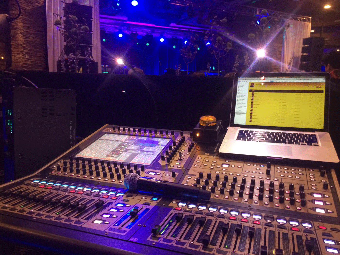 A microphone and laptop sit on top of a sound board