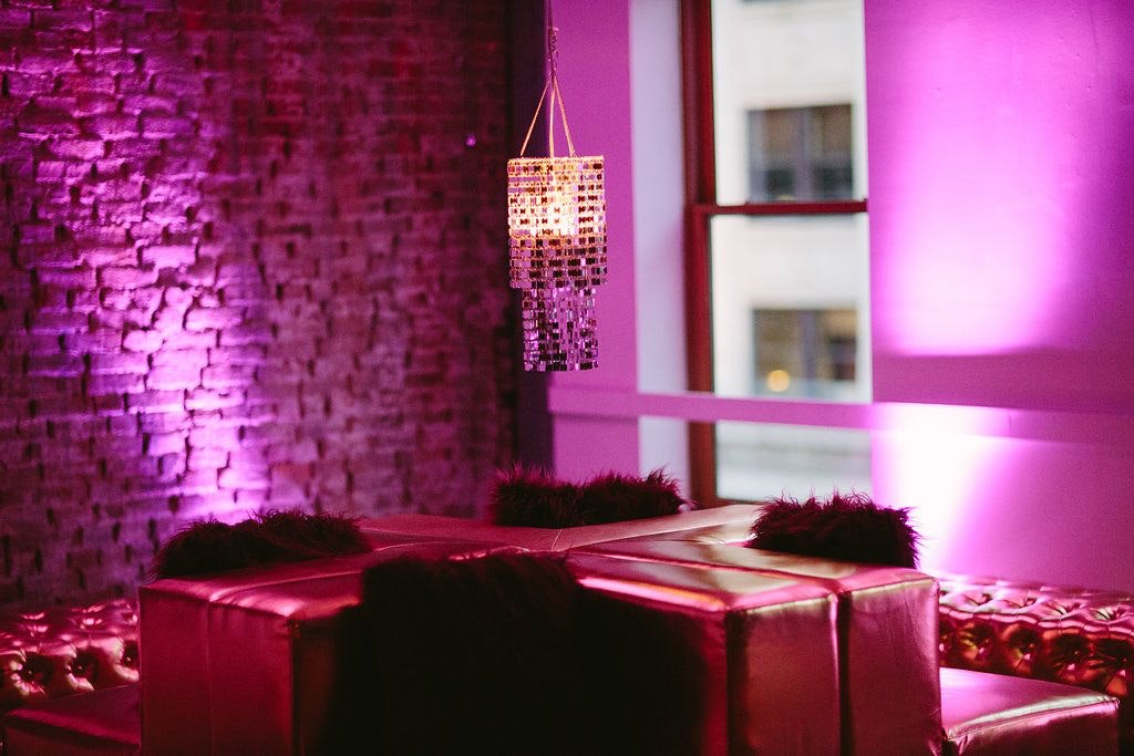 Shiny Couches And A Silver Chandelier Are In A Pink Room