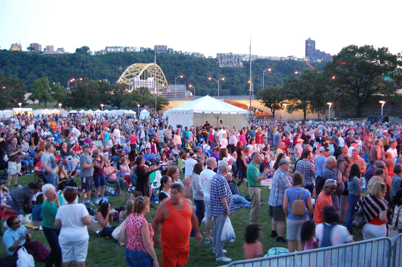 large crowd of people stands in a park
