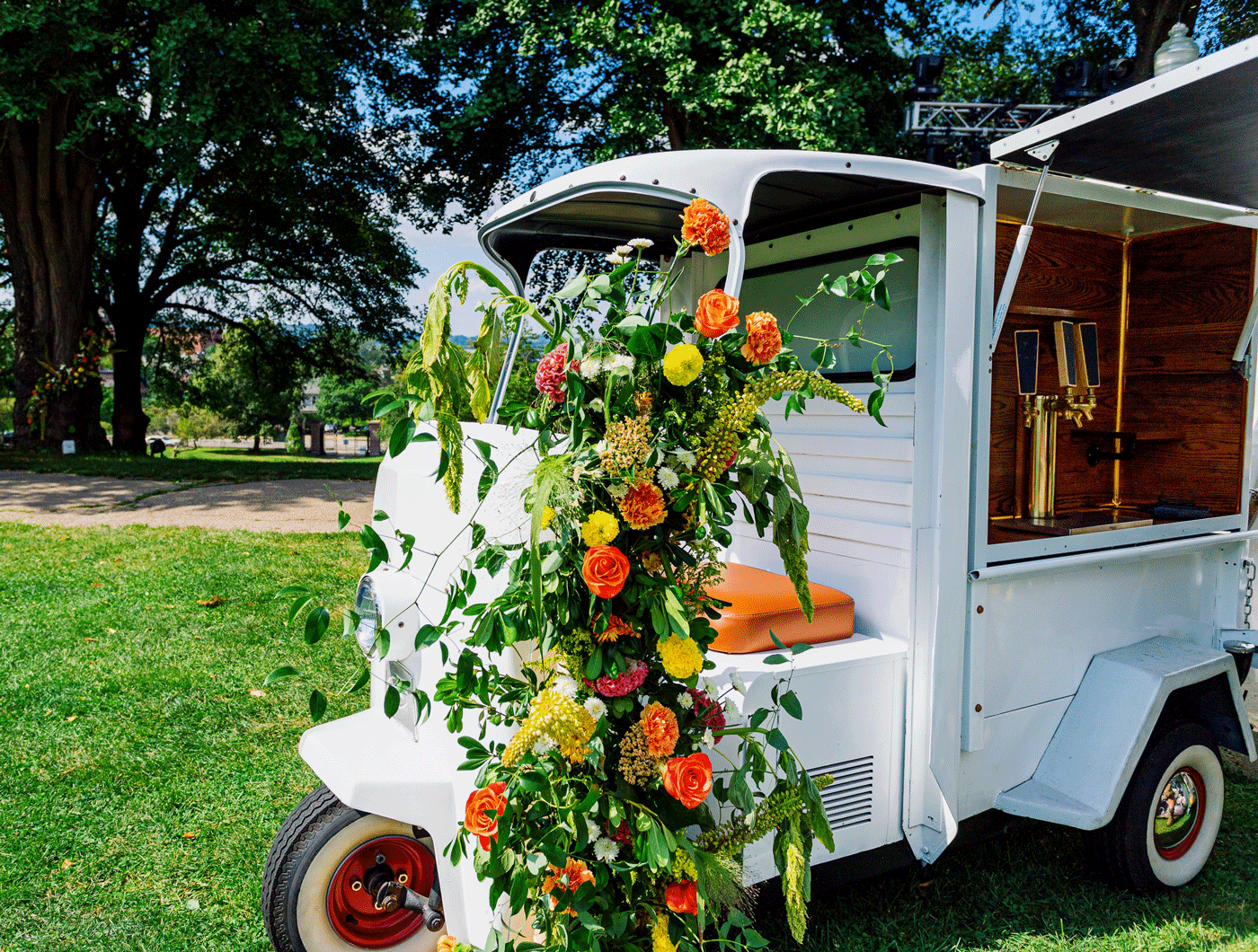 A small vehicle with bar taps in the side is adorned with flowers