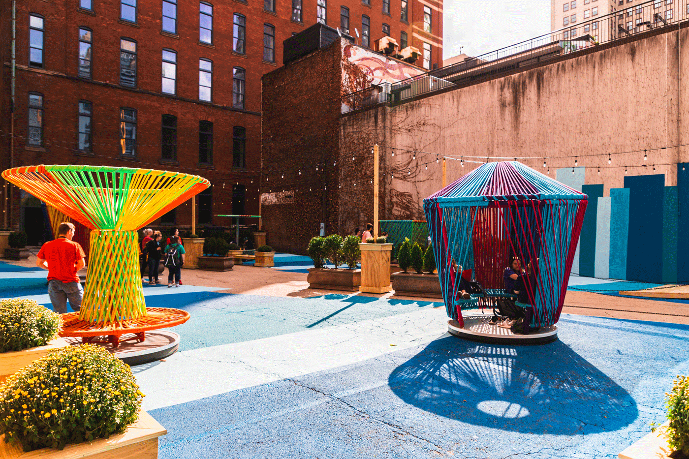 Multicolored, string, seating art pieces in a blue painted courtyard