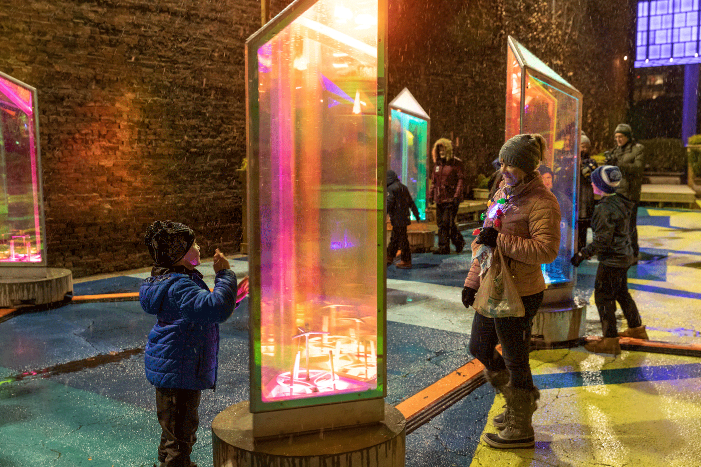 An Adult And A Child Interact With A Colorful Sculpture