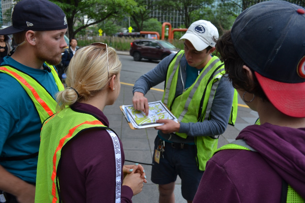 Three people look onward as a person points to a map.