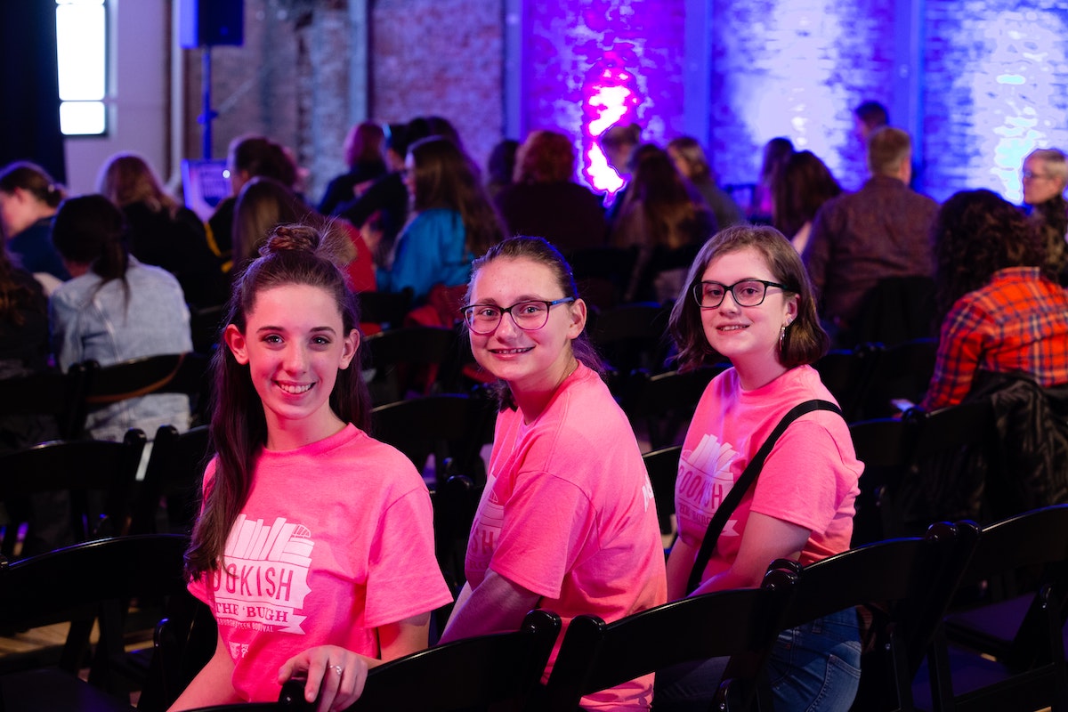 Three people sit facing the camera in matching shirts