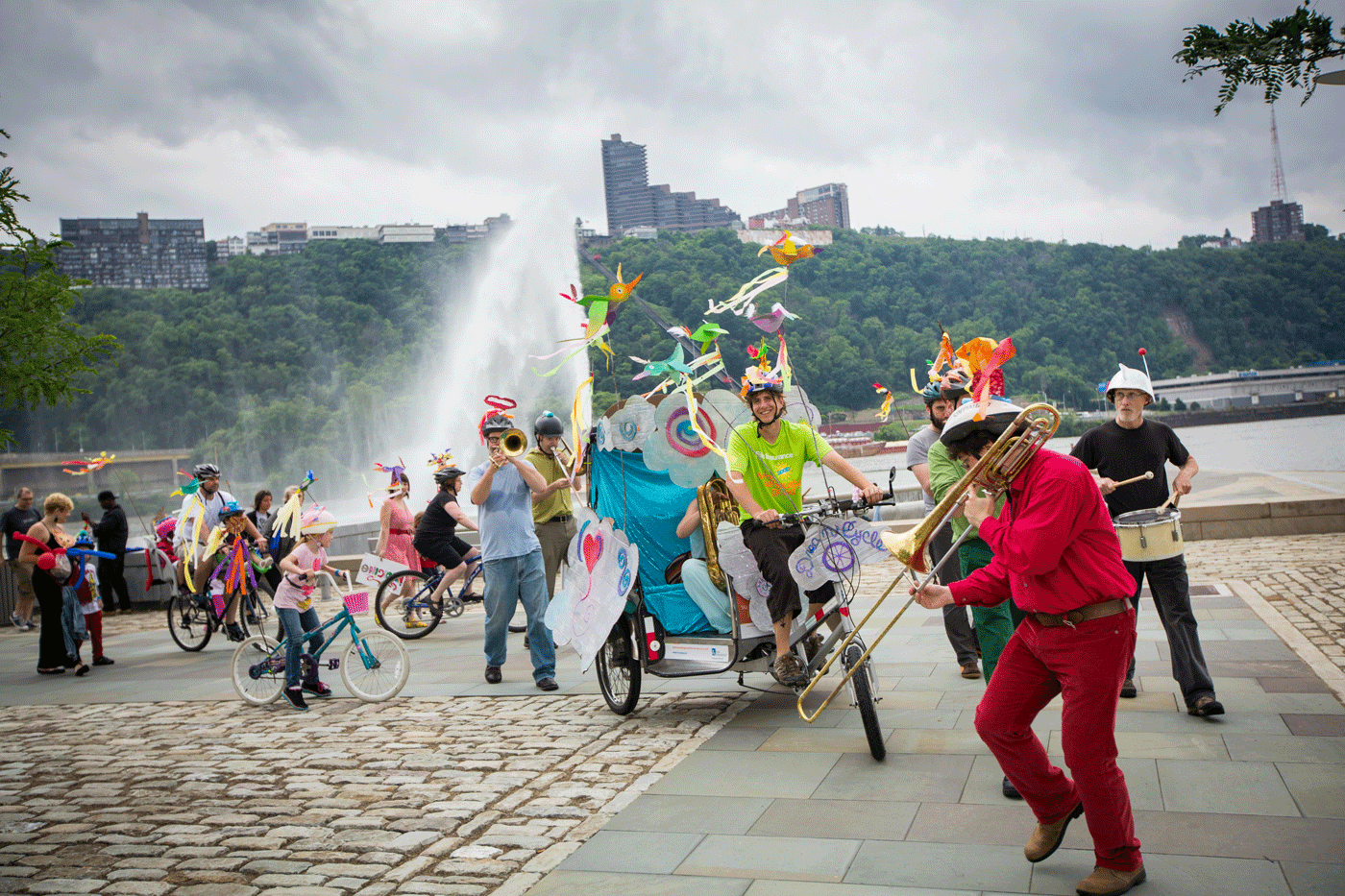 A group of performers in colorful outfits play music and ride bikes outside