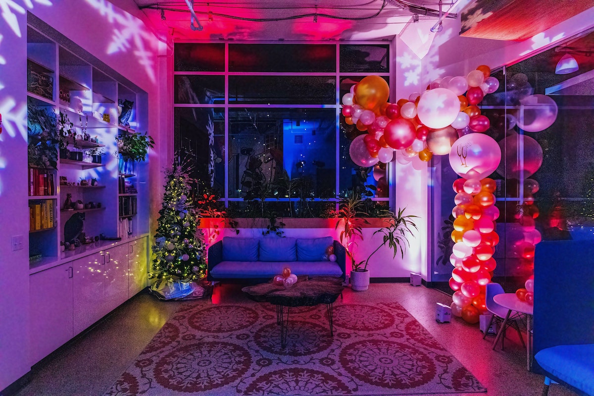 A room with a couch has a balloon arch and colorful uplighting