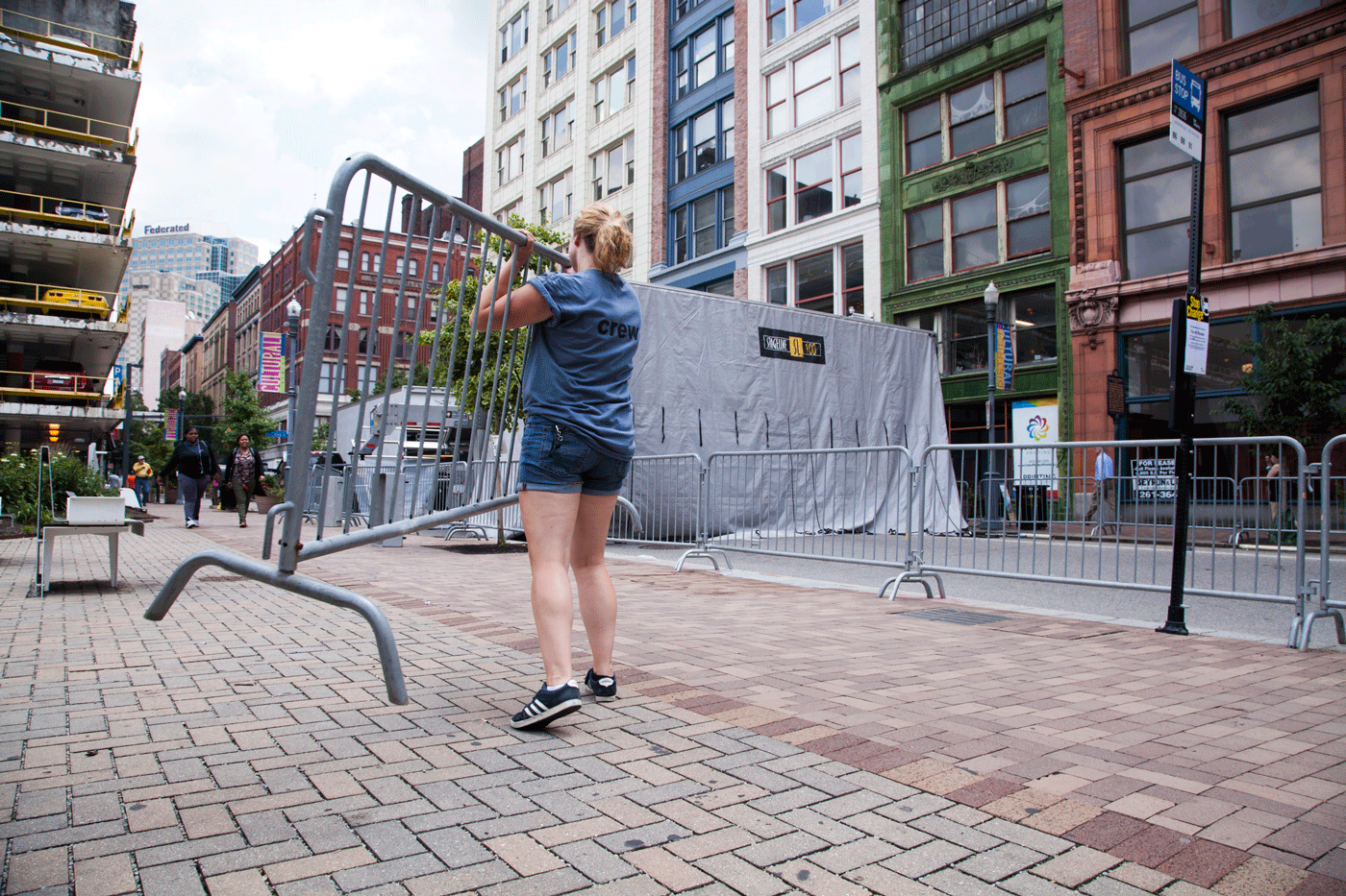 A woman carries a piece of bike rack towards a stage