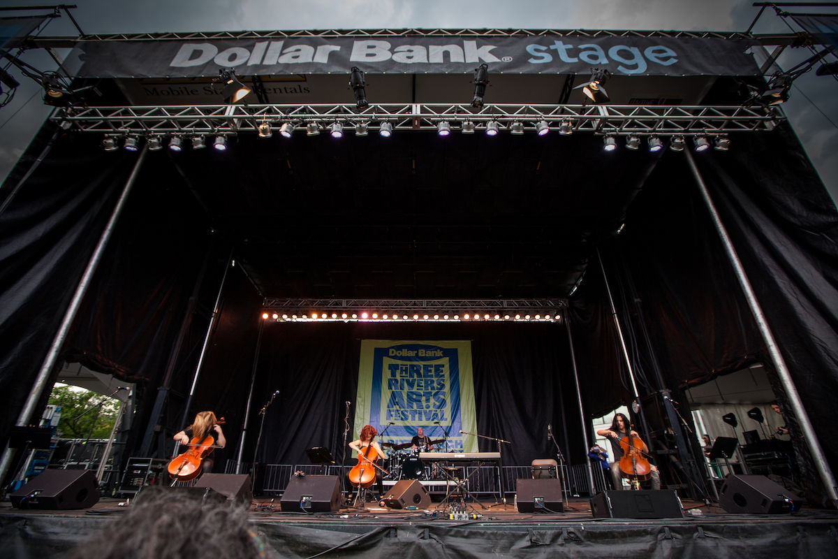 A stage with three people playing cellos