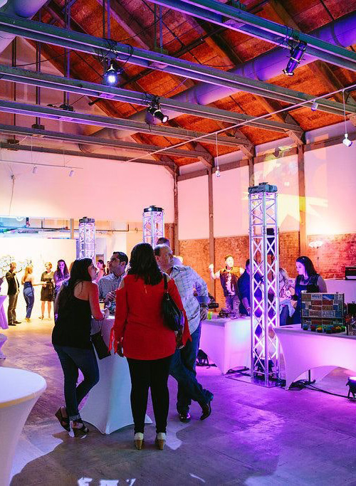 People standing around a high top table at an indoor event.