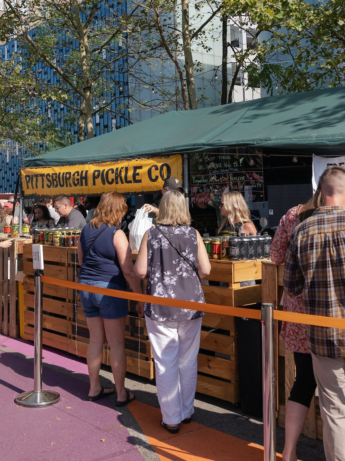 People Wait In Line In Front Of A Vendor Tent