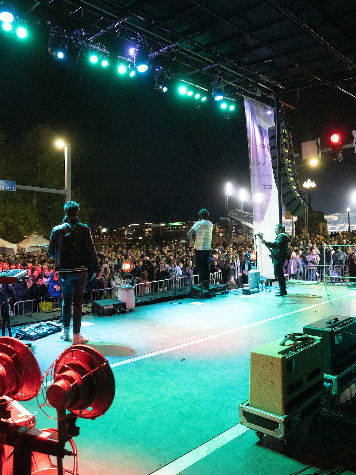 A Full Band Plays On A Stage In Front Of A Large Crowd