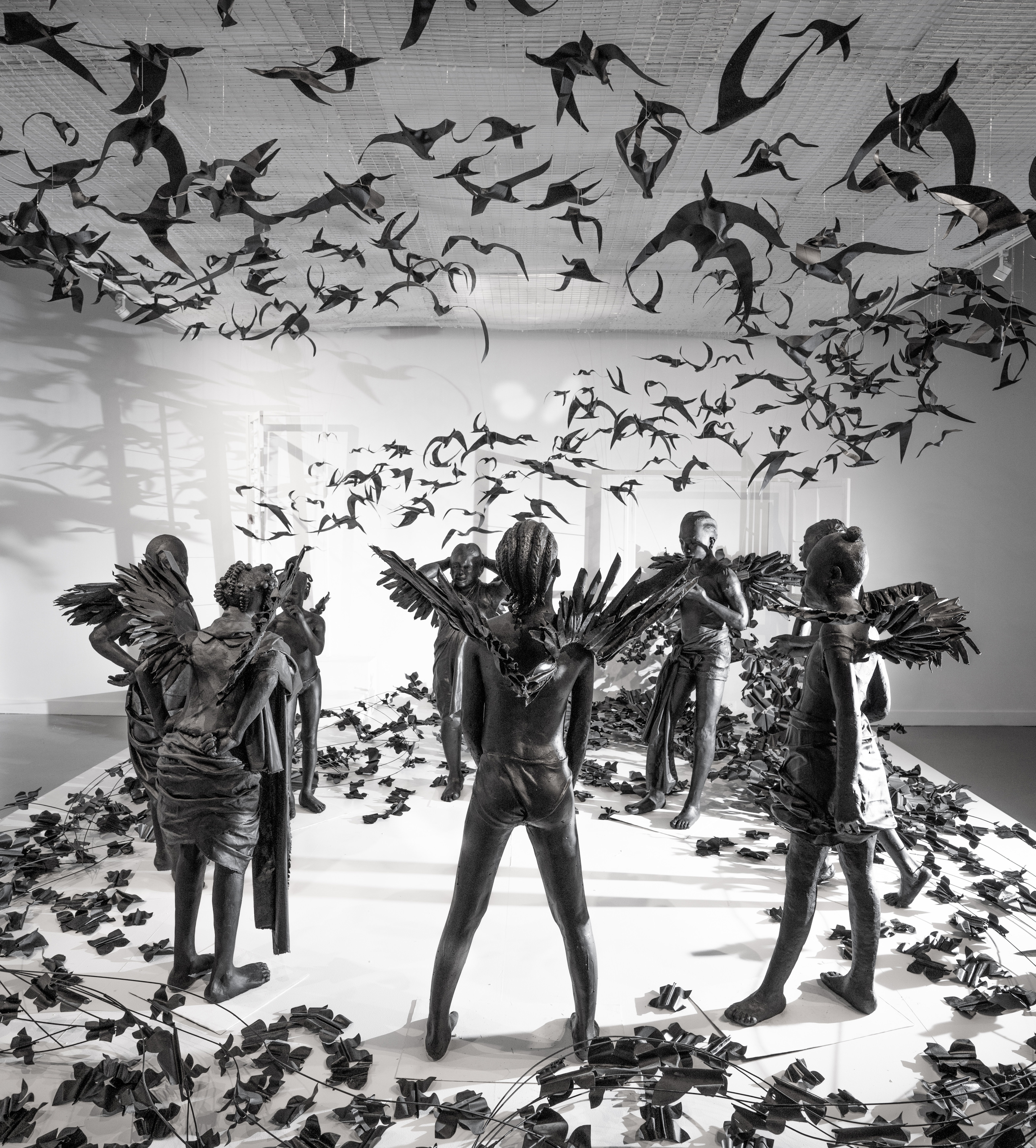 black sculptures with wings are surrounded by black bird sculptures
