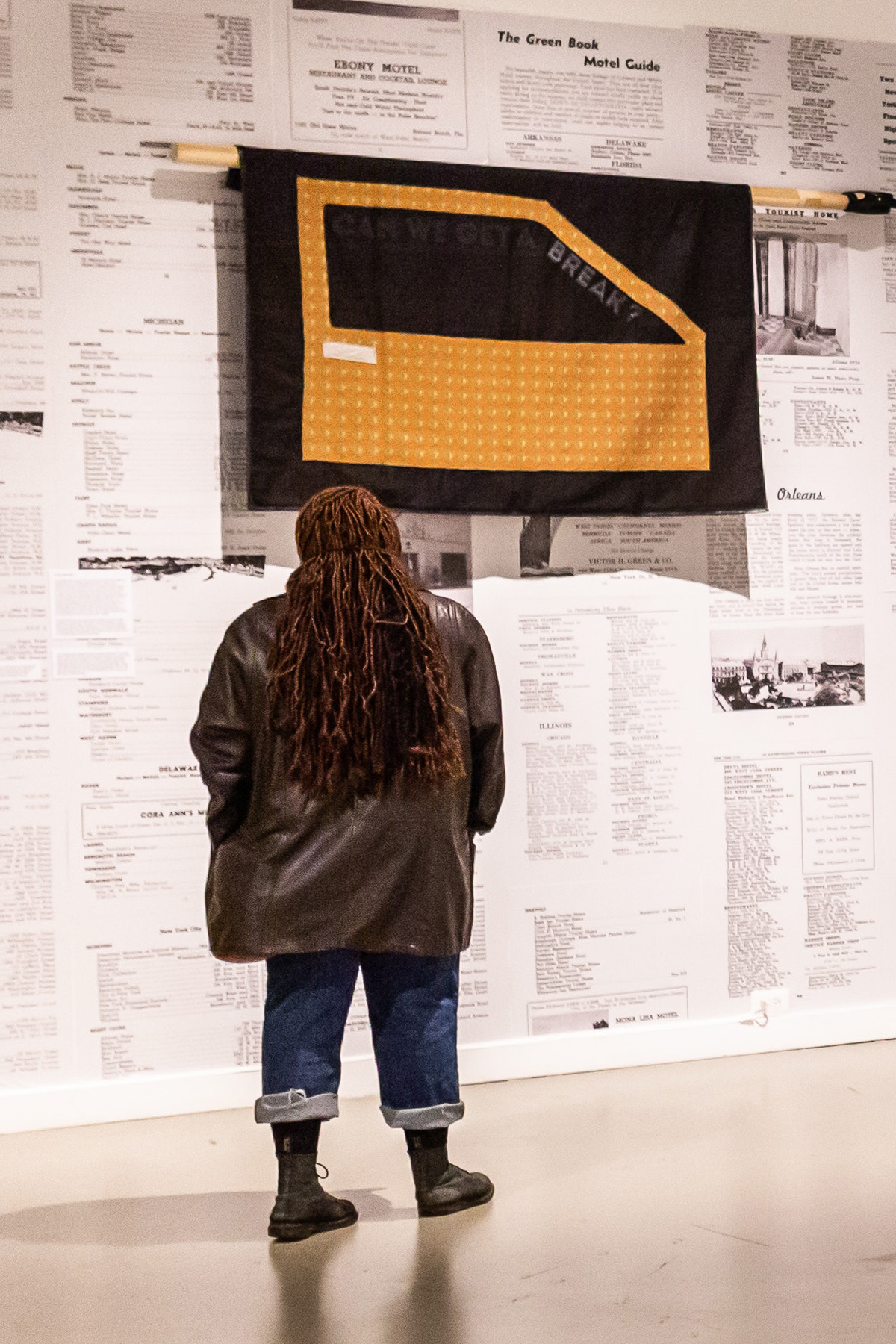 Person Stands In A Gallery Looking At Artwork On A Wall