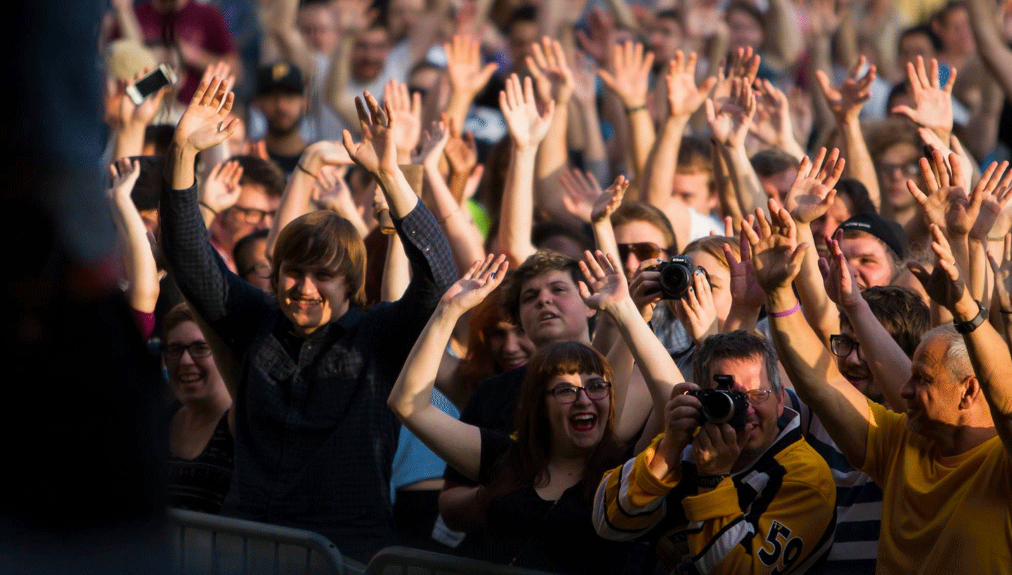 A crowd looks onward with their hands raised in the air