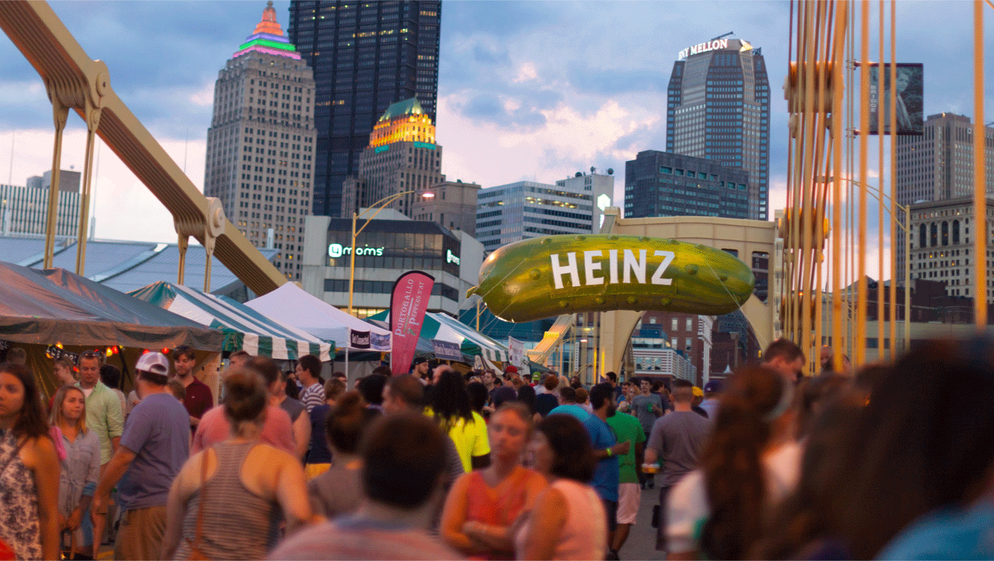 A Heinz pickle balloon is hung from the bridge with the city of Pittsburgh in the background