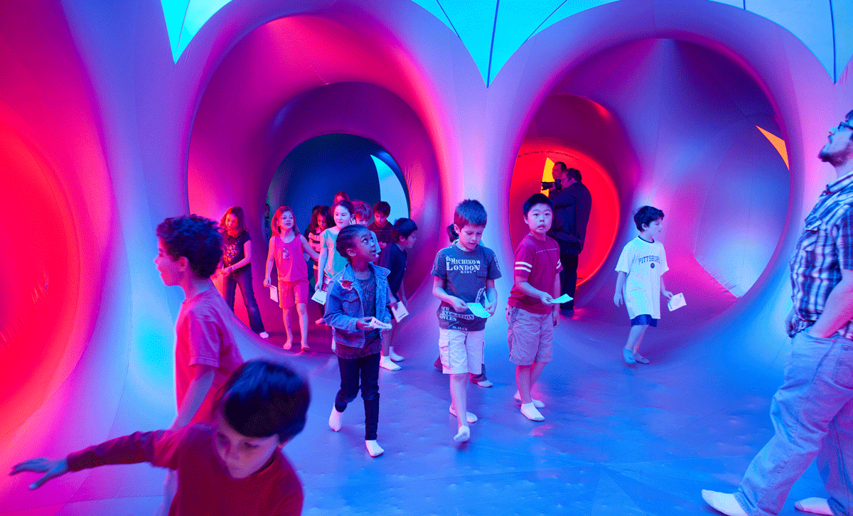 Group of children running through colorful lit of building