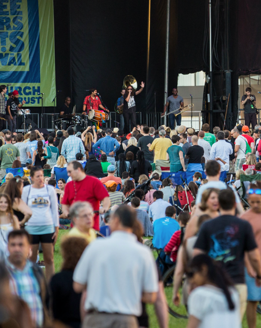 A band plays on a stage outdoors in front of a large crowd