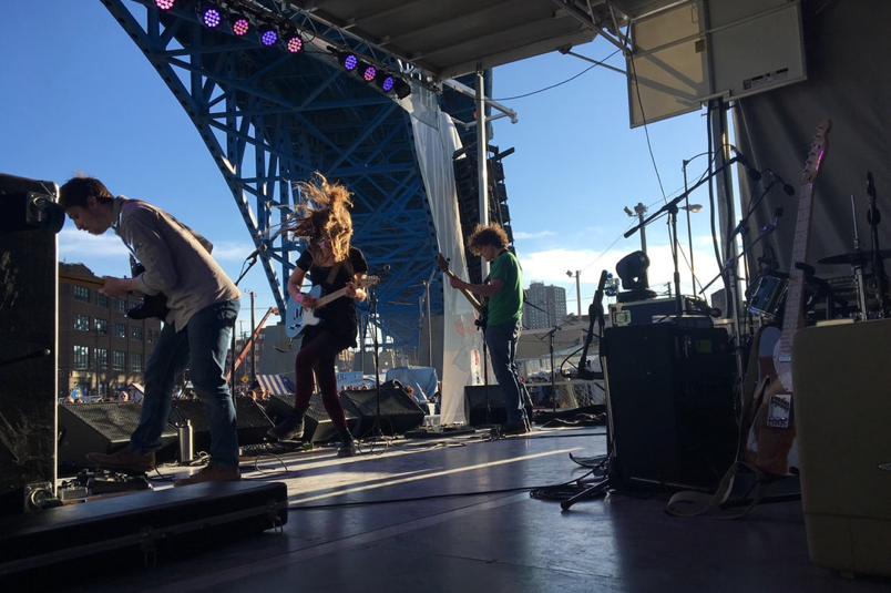 A band performs on a stage under a bridge