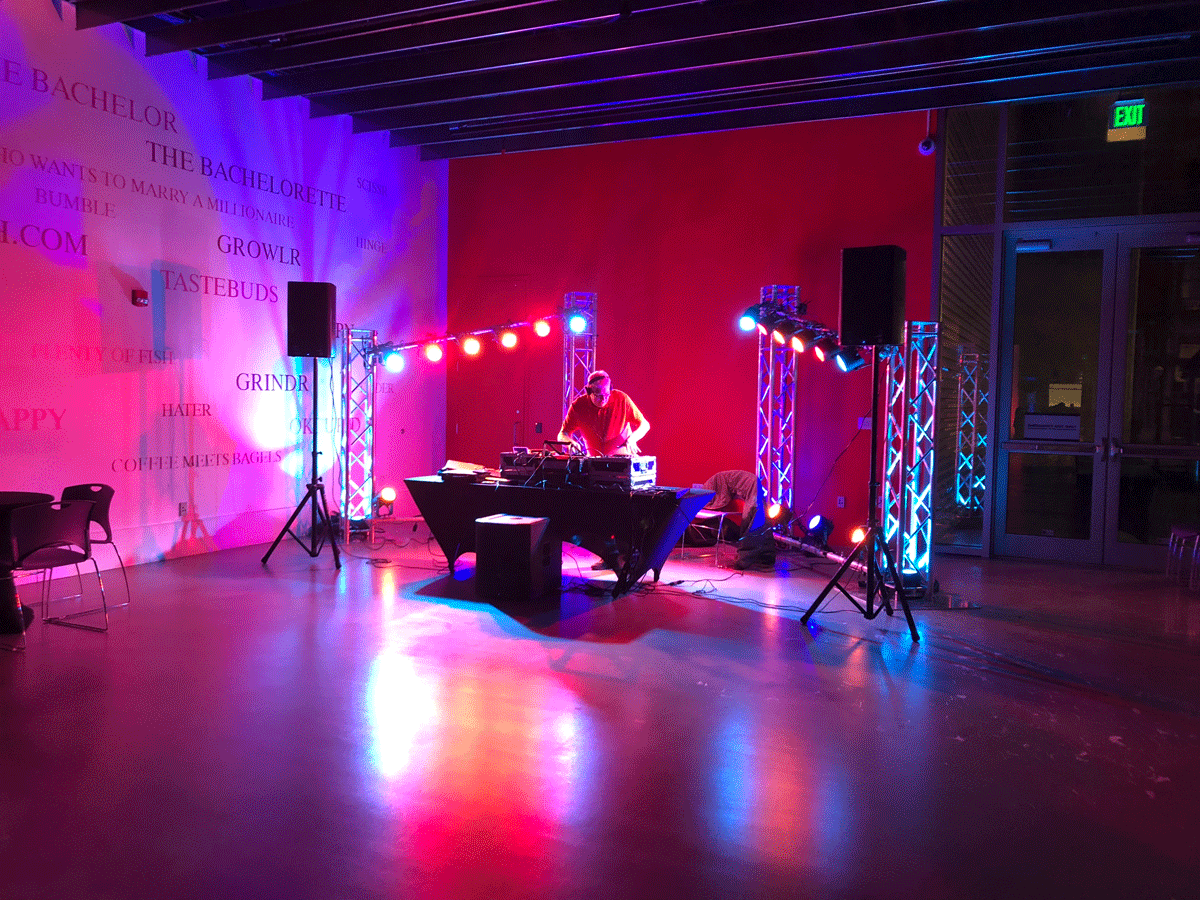 A DJ performs at a table surrounded by lights