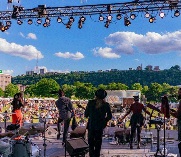 A band plays on an outdoor stage in front of a crowd