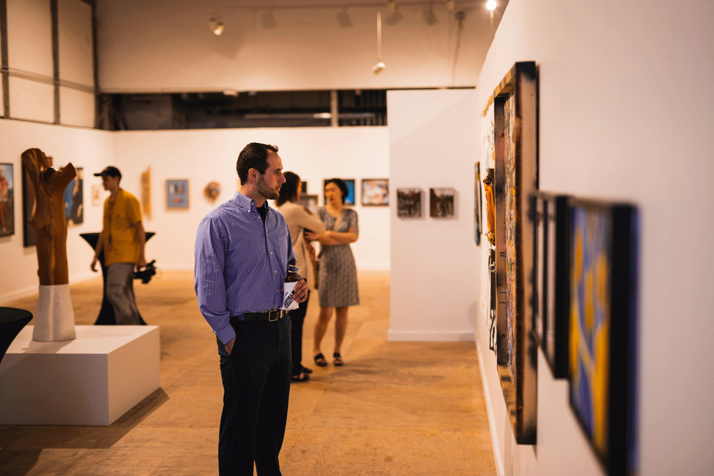 A person looks at artwork hanging on a gallery wall