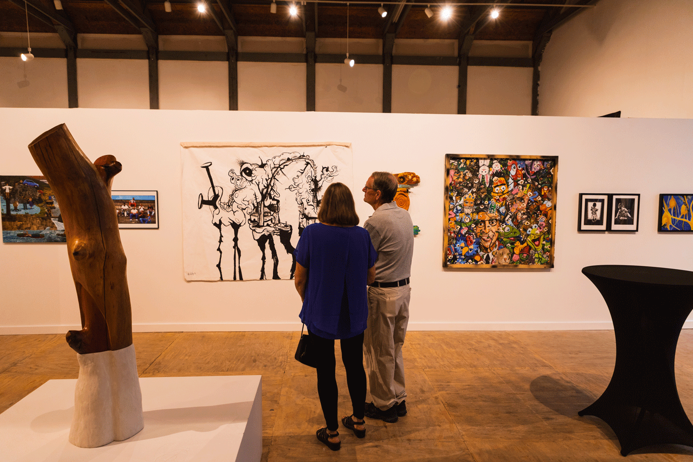 Two people look at art on the walls of a gallery