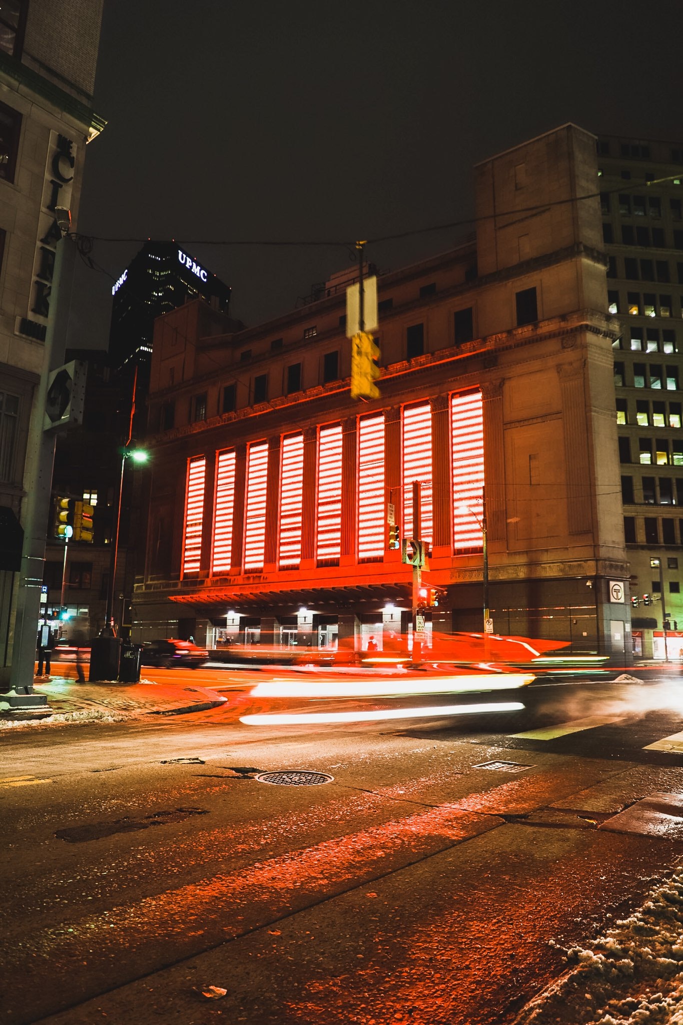 A red light installation is affixed onto the side of a building
