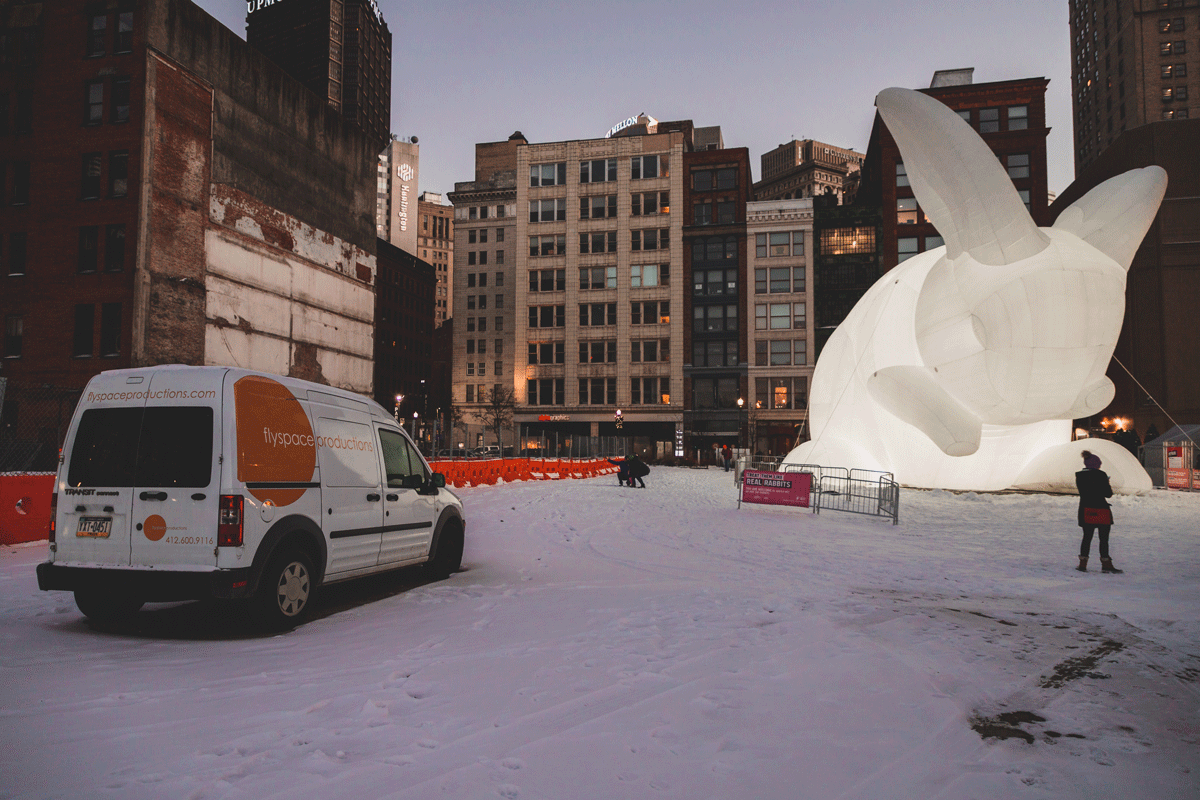 A Giant White Inflatable Rabbit Stands in A Snow Covered Lot