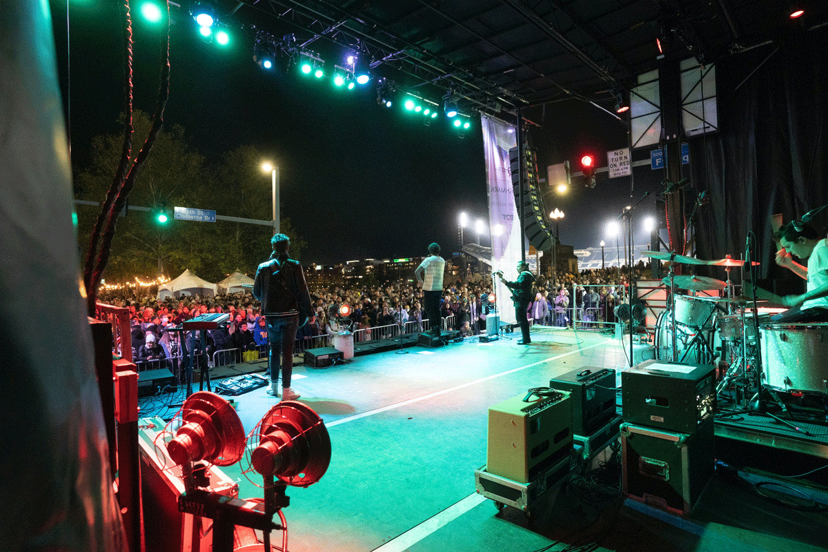 A Band Plays On A Stage Outside At Night